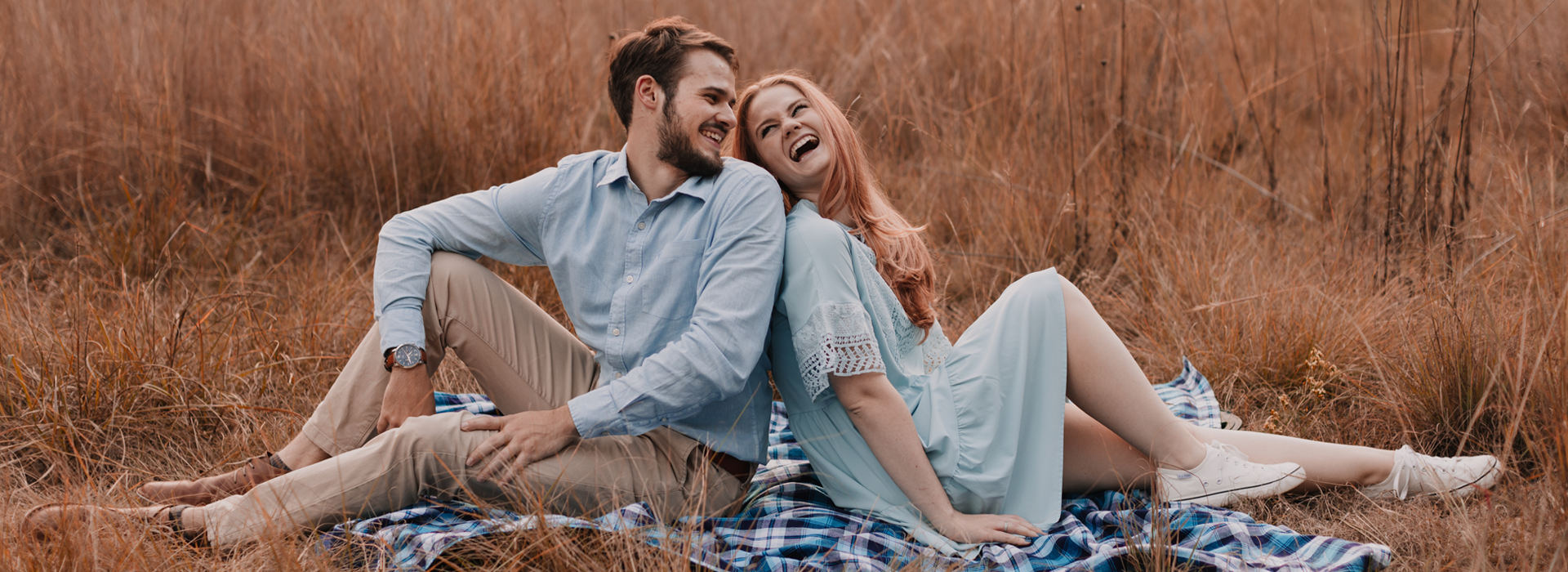 The couple sitting on the grass laughing